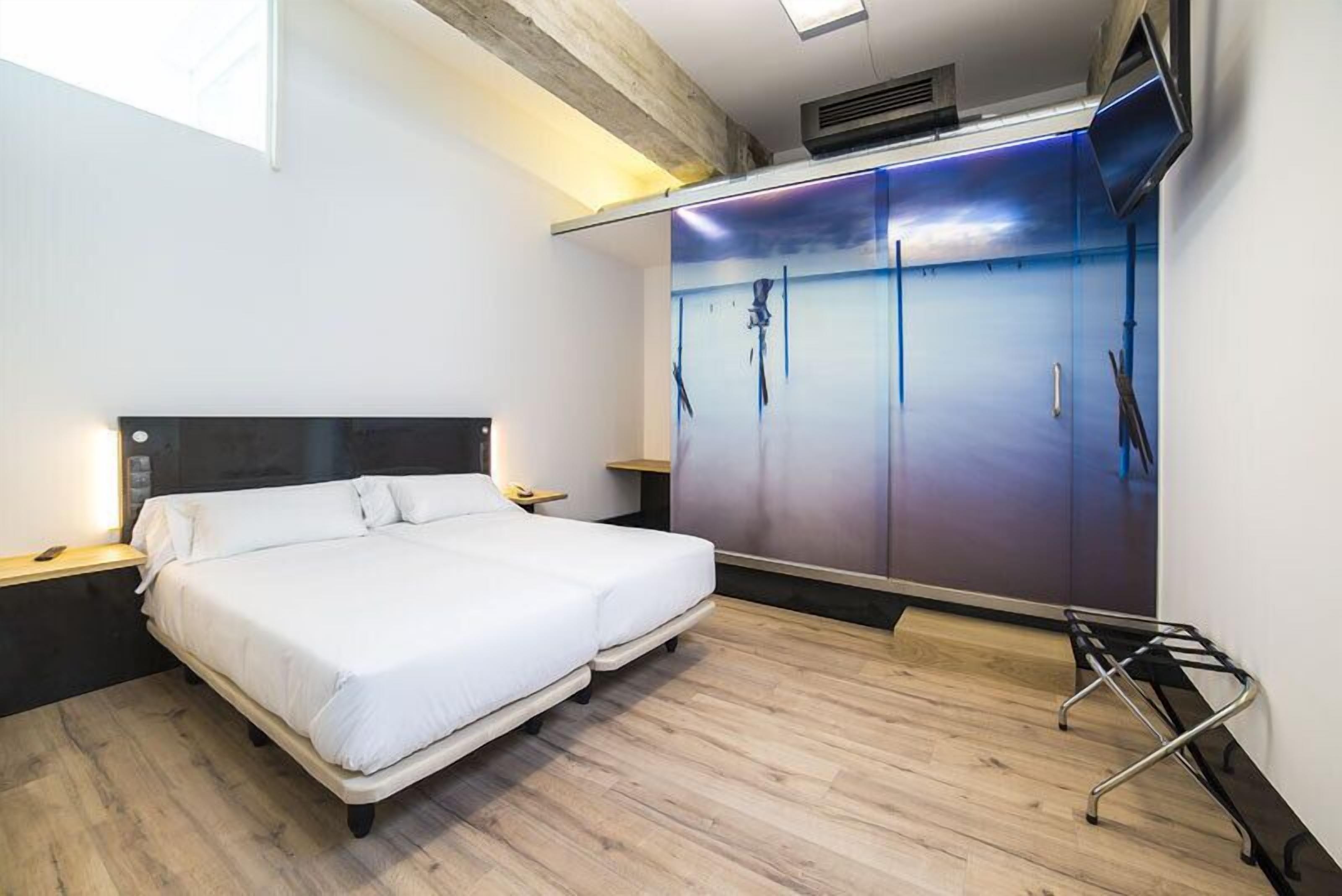 A modern bedroom with a bed, a wardrobe, and a TV.