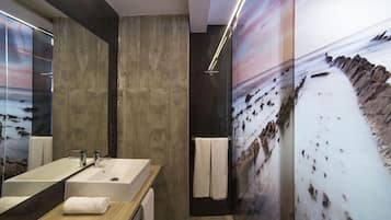 Une salle de bain moderne avec un grand miroir, deux lavabos et une douche.
