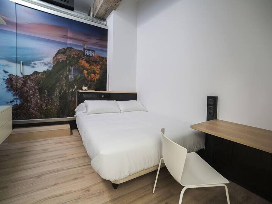 Un dormitorio con cama, escritorio, silla y un ventanal con vistas panorámicas.