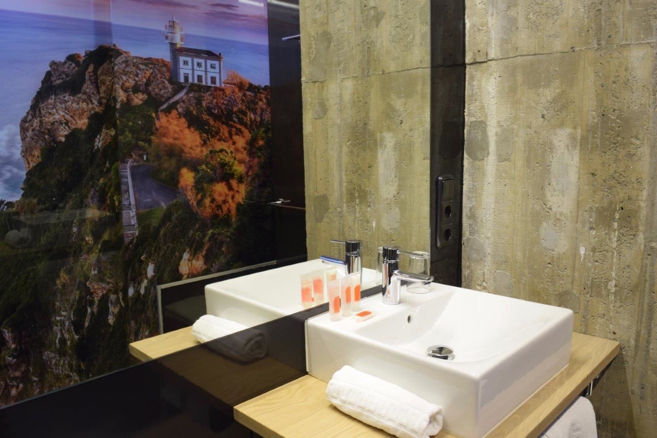 A modern bathroom with a large mirror, two sinks, and a wooden vanity.