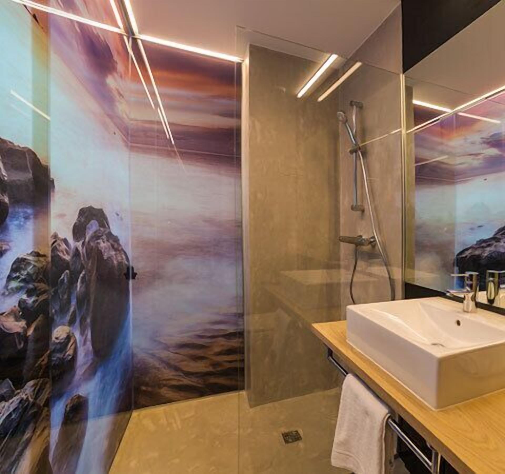 A modern bathroom with a large mirror, a shower, and a sink.