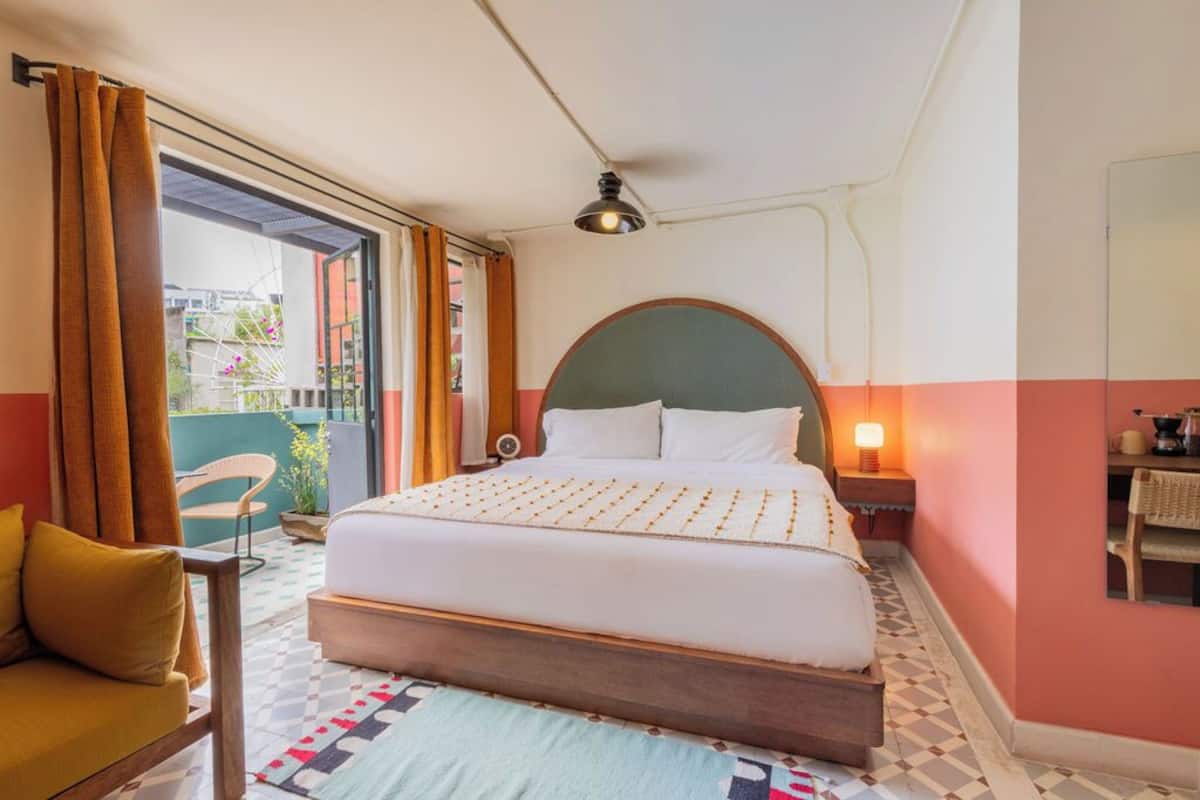 Habitación de hotel con una cama grande, una mesita, una silla y vistas al balcón exterior.
