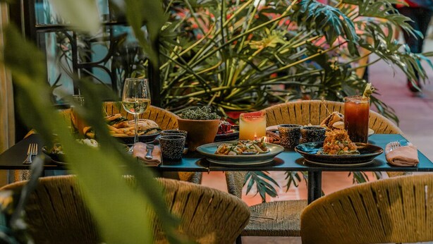 Una mesa puesta con platos de comida, vasos y una bebida.