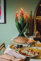 Una mesa de comedor con un centro de mesa de cactus verde, platos de comida, copas de vino y una hogaza de pan.