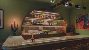 Zona de bar con mostrador de mármol, varias botellas y una variedad de plantas y flores.