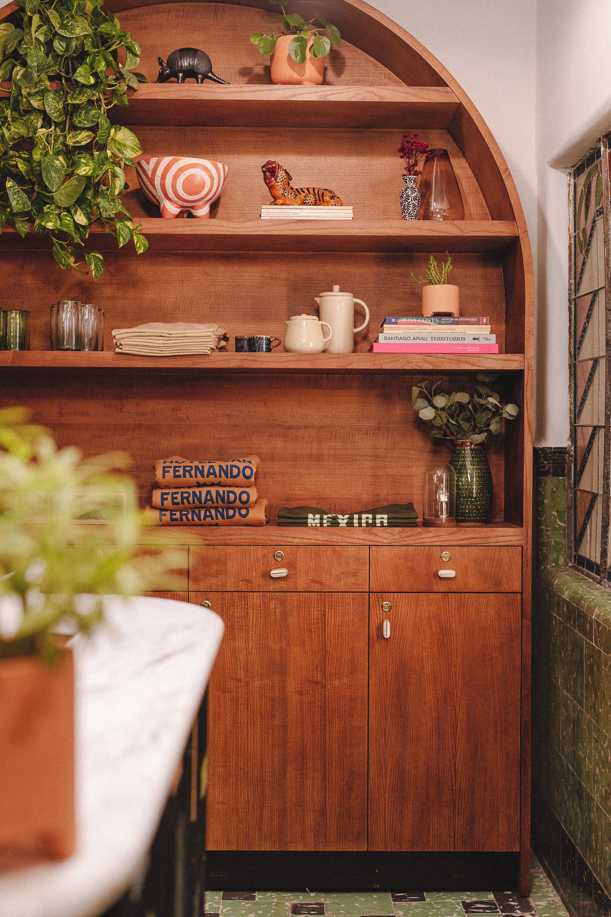 A wooden shelf with decorative items, a plant, and a sign reading "FERNANDO FERNANDO."