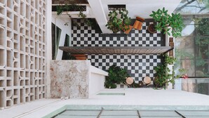 Un espacio exterior moderno con suelo a cuadros, plantas en macetas y un banco de madera.