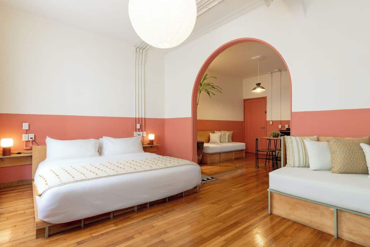 Habitación de hotel con una cama grande, un sofá, un escritorio y un espejo.