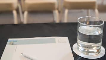 Ein Glas Wasser auf einem Untersetzer neben einem Dokument mit einem Stift auf einem Tisch.