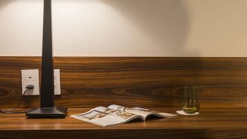 A desk with a lamp, a glass of wine, and a magazine.
