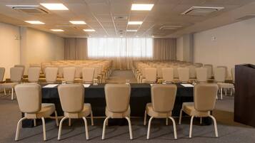 A conference room with rows of chairs, a long table, and a podium.