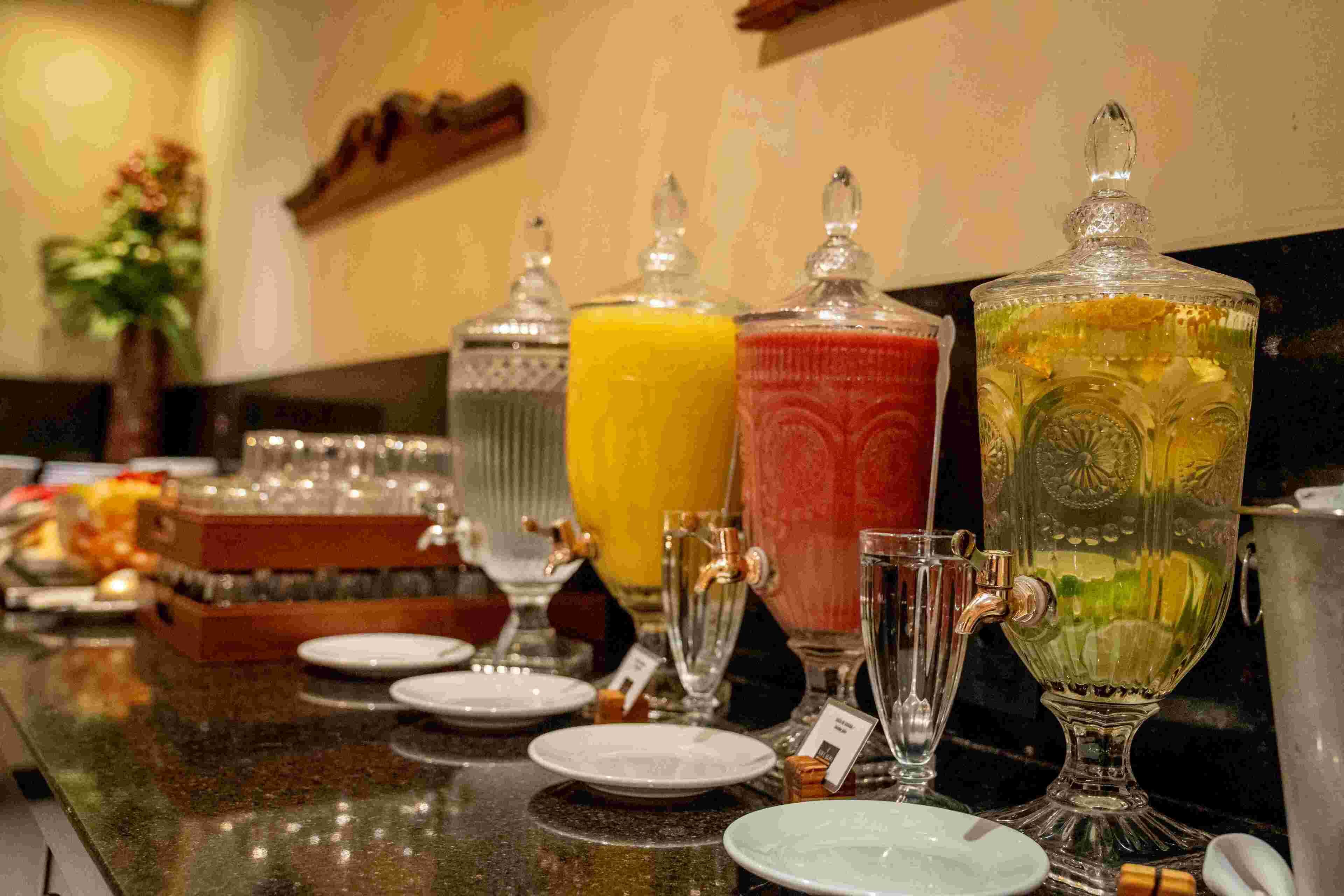 Una barra de desayuno con varios recipientes de vidrio con bebidas y platos.