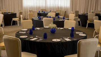 A conference room with round tables, beige chairs, and blue glassware.
