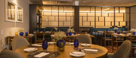 A restaurant with round tables set for dining, featuring blue glassware and white flowers.