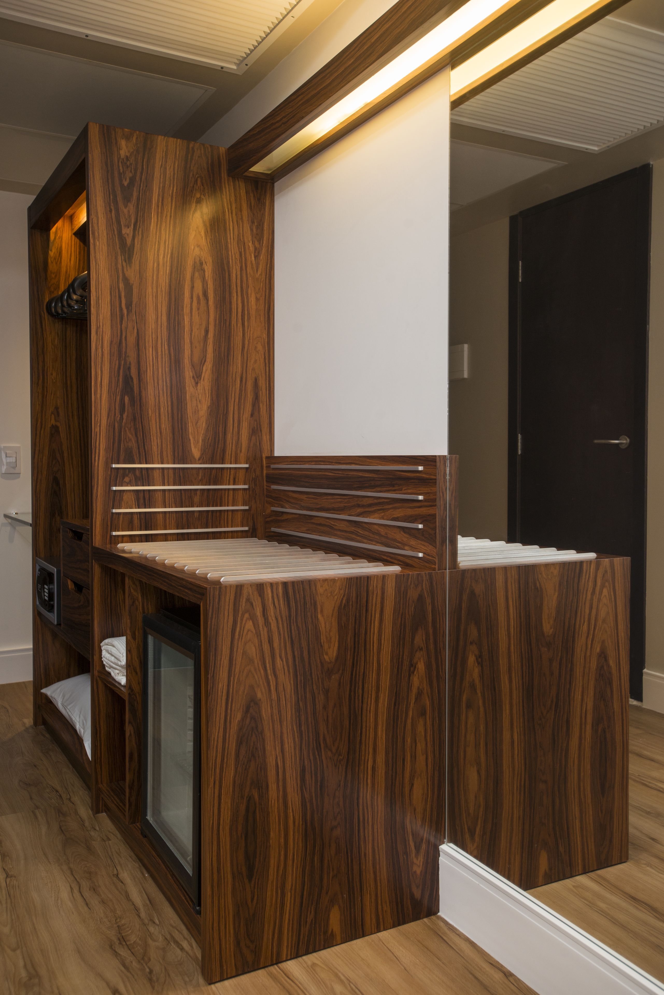 A compact, modern room with built-in wooden furniture, a small seating area, and a door.