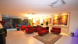 A modern living room with red sofas, a large rug, and a chandelier. - PALACE HOTEL (Santo Antonio de Jesus)