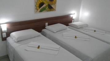 Ein Hotelzimmer mit zwei Einzelbetten, jeweils mit weißer Bettwäsche und einem ordentlich gefalteten Handtuch. Ein Holz-Kopfteil, eine Wandleuchte und ein Gemälde von Sonnenblumen sind über den Betten angebracht.