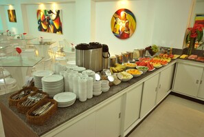 Montaje de bufé con diversos alimentos, platos y cubiertos.