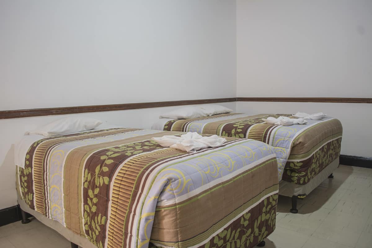 Een kamer met twee bedden, elk met een gebedrukte sprei en kussens.