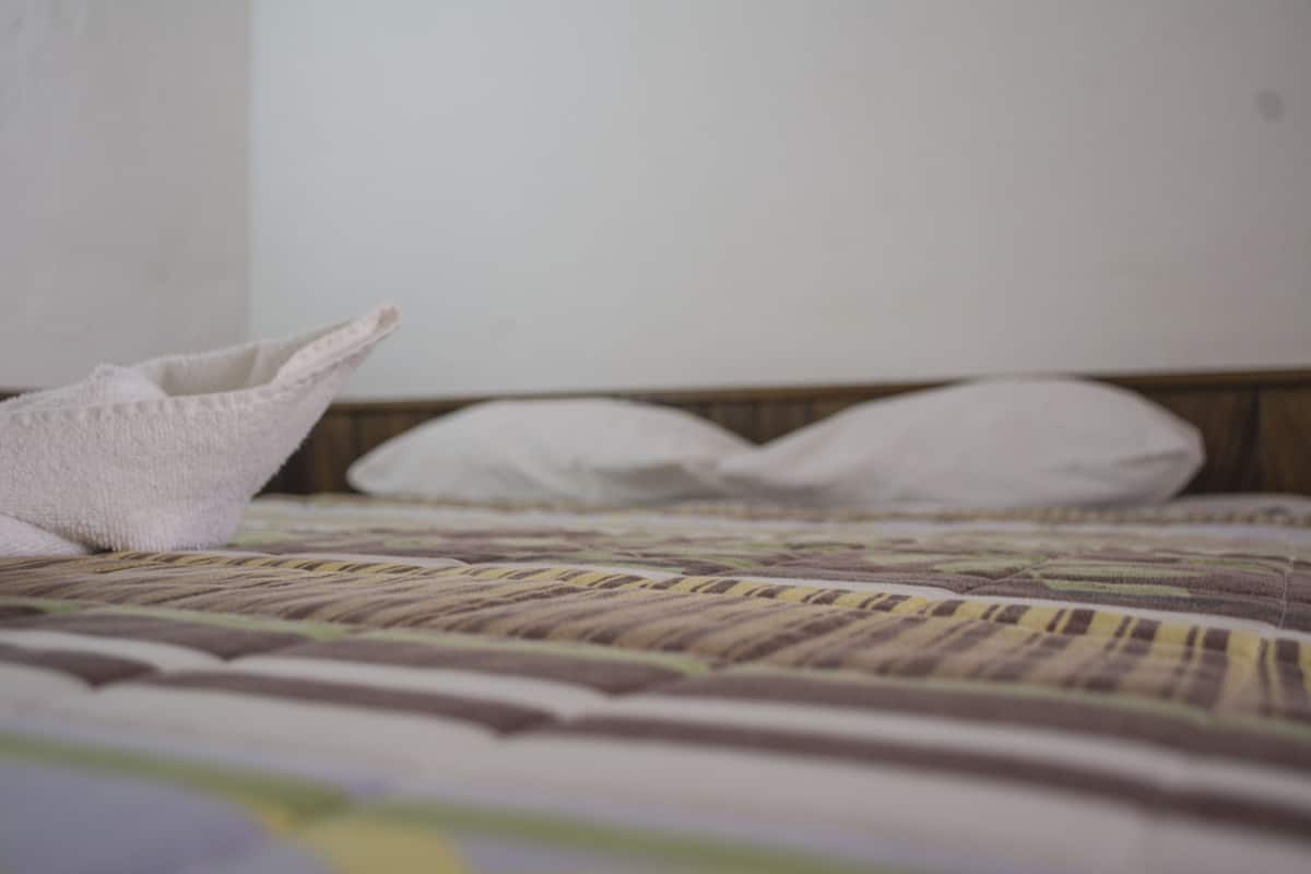 Een bed met een gestreepte spreideken en kussens.