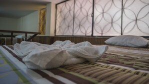 Una cama bien hecha con una colcha a rayas y una toalla blanca doblada encima.