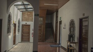 Un pasillo con puerta de madera, escalera y barandilla de metal.