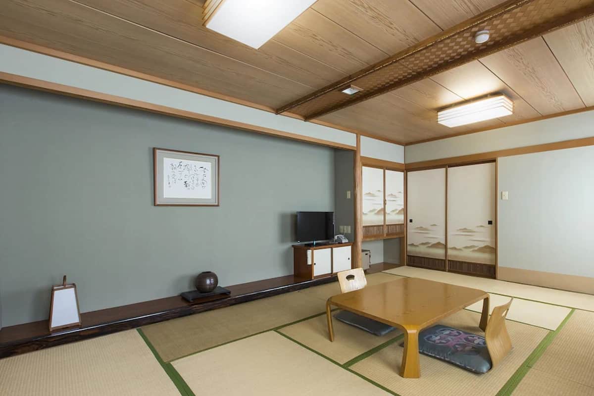 A traditional Japanese room with tatami flooring, a low table, and sliding doors.