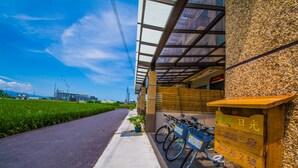 A building with a covered entrance, bicycles parked outside, and a clear sky. - Green Field & Sunshine (Luodong)