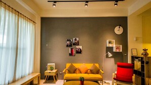 A living room with a sofa, a red chair, a coffee table, and a clock on the wall. - Green Field & Sunshine (Luodong)