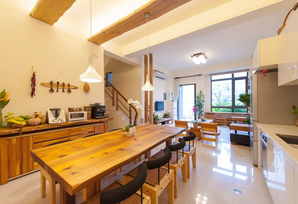 A modern kitchen with wooden countertops, a large wooden dining table, and built-in appliances. - Songtian B&B (Jiaoxi)