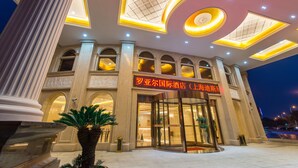 A hotel entrance with a grand facade, large windows, and a prominent sign. - Royal International Hotel Disneyland and Wild Animal Park Branch (Shanghai)
