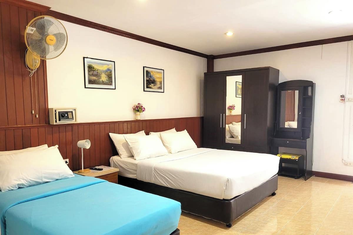 A hotel room with two beds, a wardrobe, a mirror, and two framed pictures on the wall.
