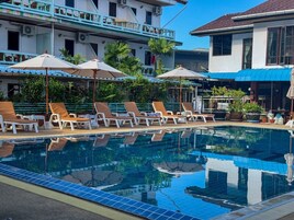 Una piscina al aire libre, sombrillas, sillones reclinables de piscina