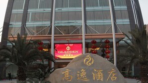 A hotel with a modern glass facade, a prominent sign for the Gladden Hotel, and traditional Chinese decorations. - Chengdu Gaoyi Hotel (Chengdu)