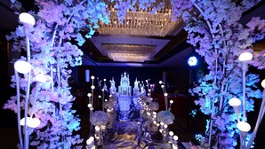 A corridor with a reflective floor, flanked by artificial cherry blossom trees and chandeliers. - Chengdu Gaoyi Hotel (Chengdu)
