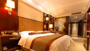 A hotel room with a large bed, a nightstand with a lamp, and a mirror. - Chengdu Gaoyi Hotel (Chengdu)