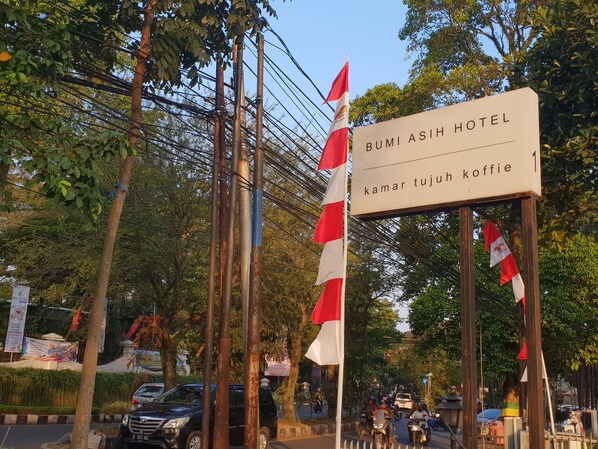 Une enseigne pour l’hôtel Bumi Asih, avec un drapeau et un groupe d’arbres en arrière-plan.