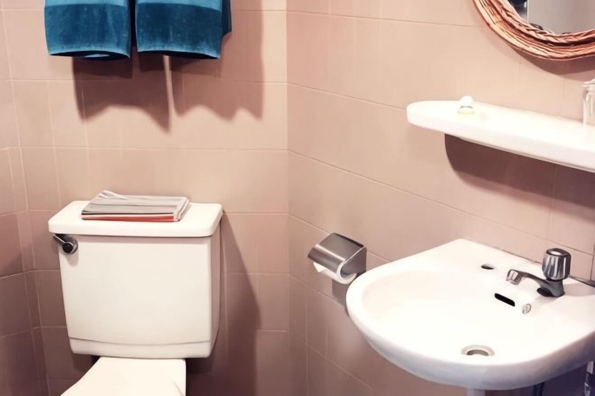 A bathroom with a toilet, a sink, and a towel rack with two towels.