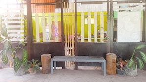 Un banc composé d’un poteau en bois et d’une structure en métal, entouré de plantes en pot et d’une clôture en bois.