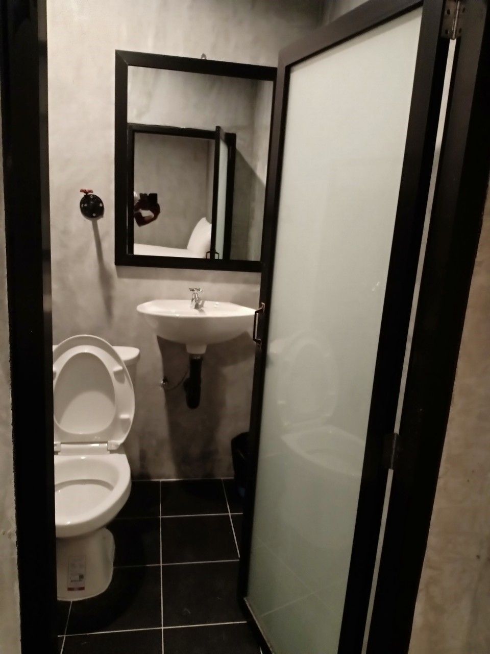 A small, compact bathroom with a toilet, sink, and mirror.