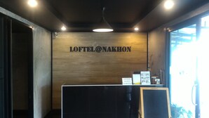 A reception area with a wooden wall, a sign reading "LOFTEL@NAKHON", and a black reception desk. - Loftel at Nakhon (Nakhon Si Thammarat)