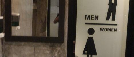 A restroom with a sink, a mirror, and a door with gender symbols indicating men's and women's facilities.