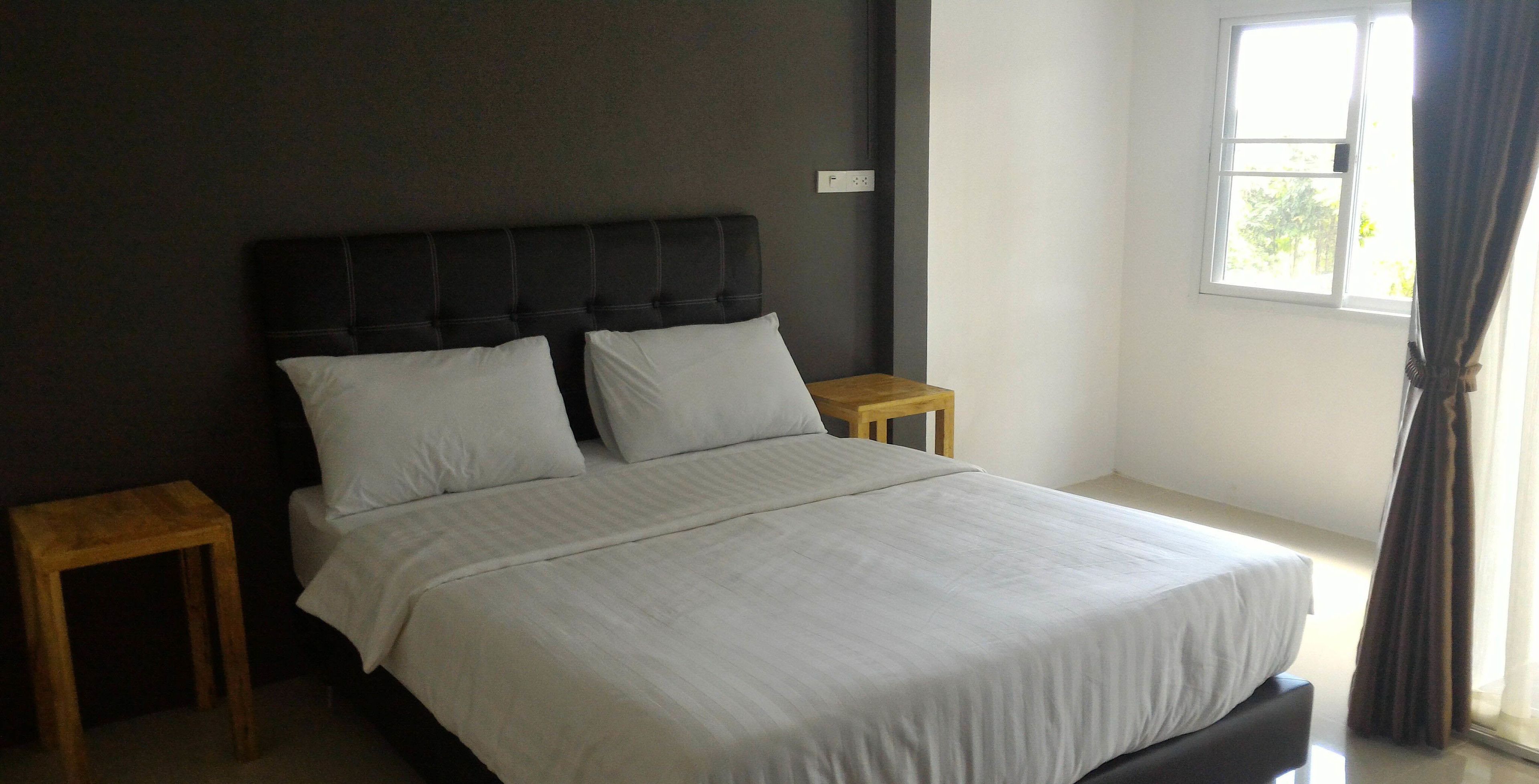 A bedroom with a large bed, two bedside tables, and a window with curtains.