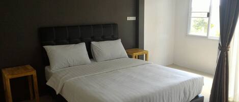 A bedroom with a large bed, two bedside tables, and a window with curtains.