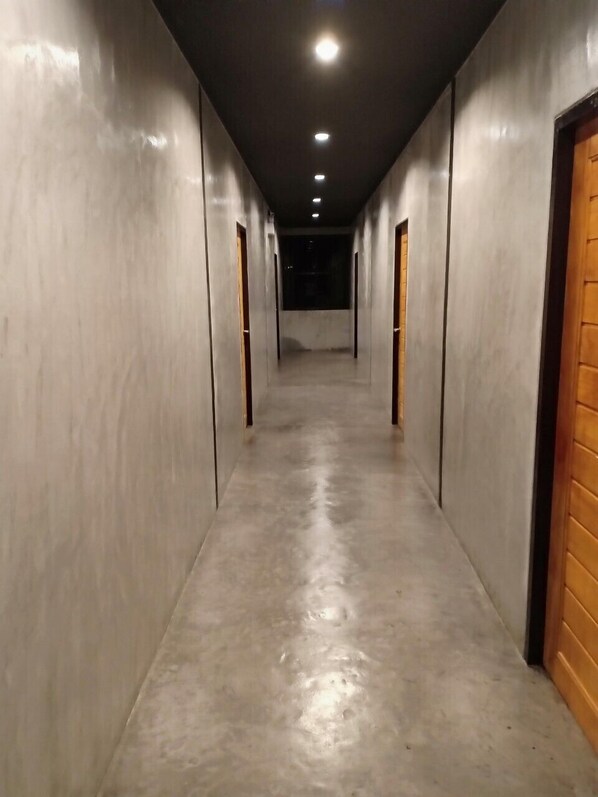 Un pasillo largo y estrecho con piso y paredes de color claro, que conduce a una zona oscura al final.