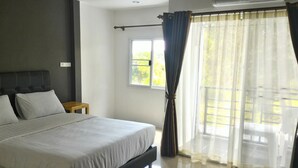 A bedroom with a bed, a nightstand, a window, and curtains. - Loftel at Nakhon (Nakhon Si Thammarat)