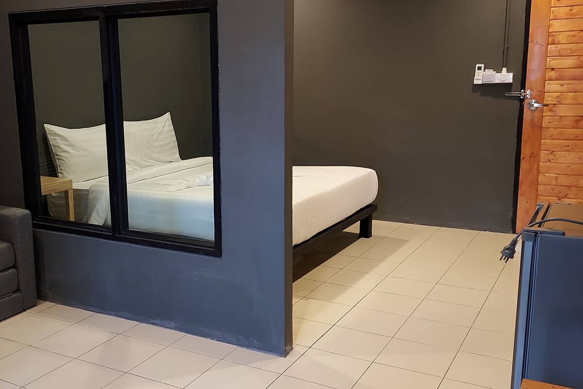 A compact room with a bed, a sofa, and a window.