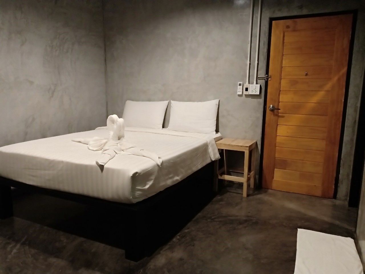 Une chambre à coucher avec un lit, une table de chevet et une porte en bois.