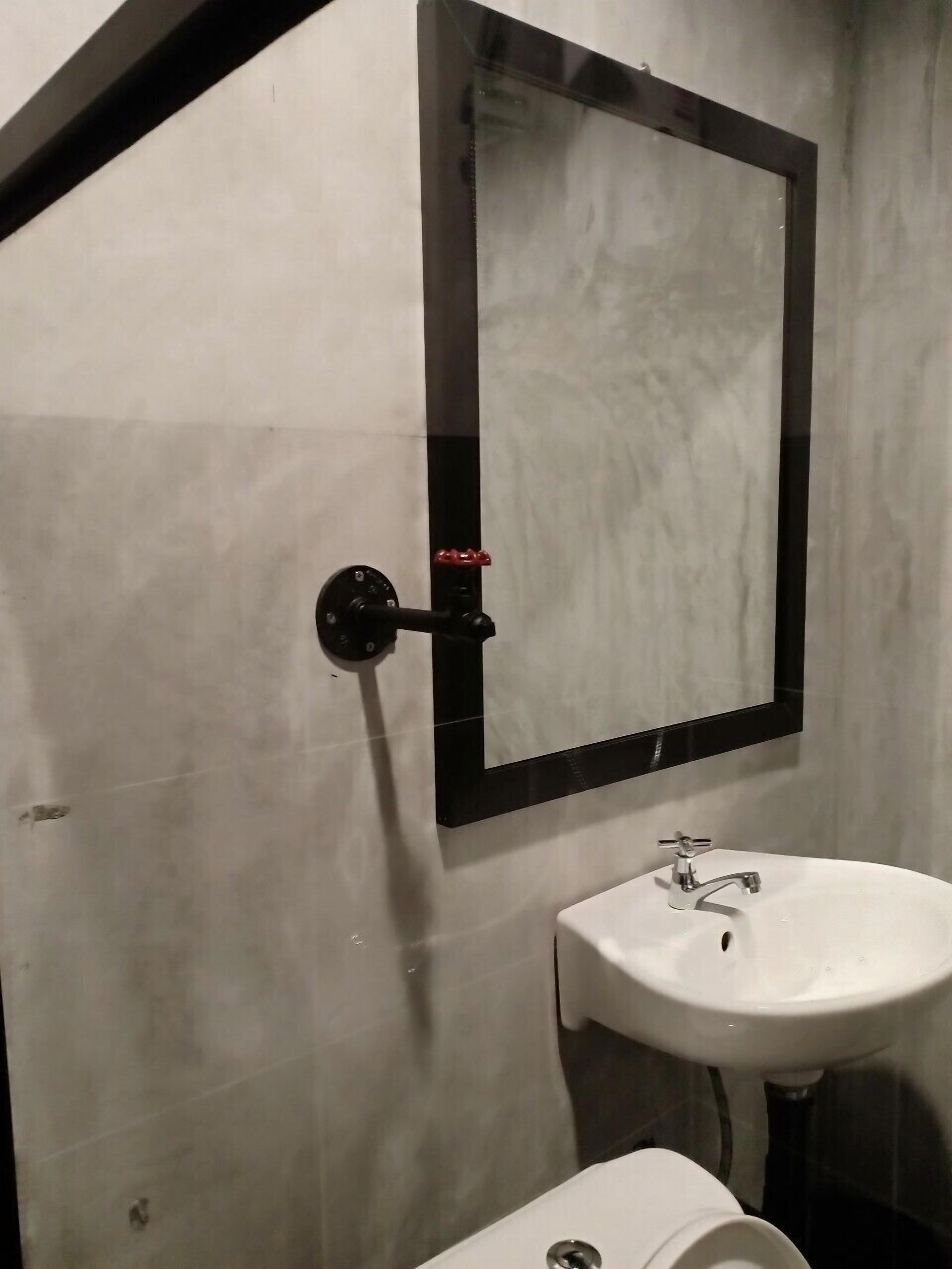 Un baño con lavamanos blanco, inodoro y espejo de marco negro.