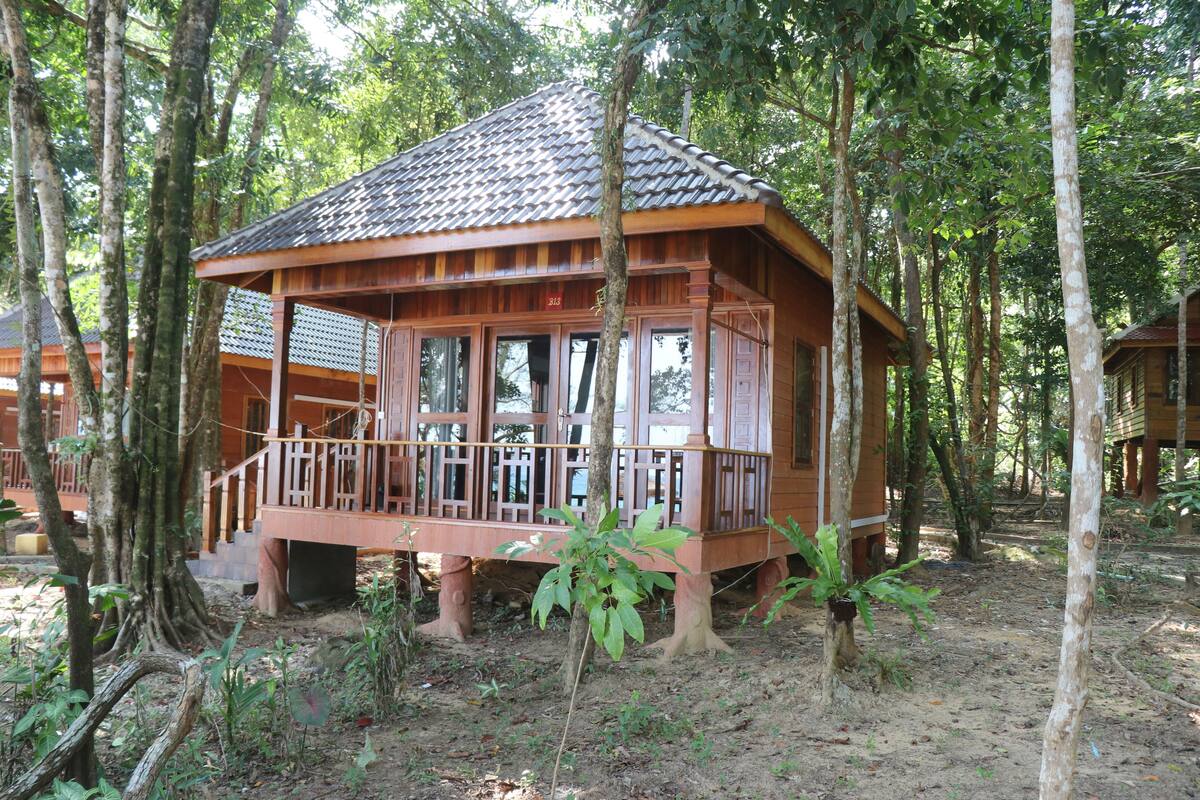 A wooden cabin with a tiled roof, surrounded by trees.